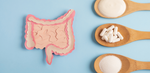 A stylized drawing of a colon next to three wooden spoons filled with white powder and capsules.