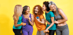 Group of five women of diverse ages in workout clothes smiling and having fun.