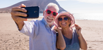 Older couple enjoying the beach in the summer, taking a selfie