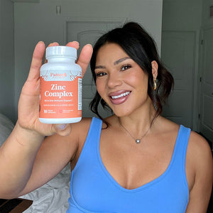 A female customer smiling while holding a bottle of Pattern Wellness Zinc Complex.