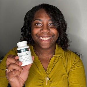 A satisfied female customer proudly displays a bottle of Pattern Wellness Quercetin.
