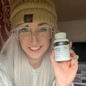 A female customer with a bright smile holding a bottle of Pattern Wellness Ashwagandha Complex.
