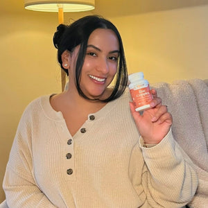A female customer with a bright smile holding a bottle of Pattern Wellness Zinc Complex.