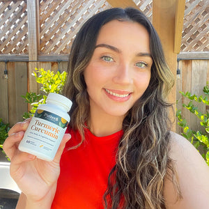 A cheerful female customer proudly displays a bottle of Pattern Wellness Turmeric Curcumin.
