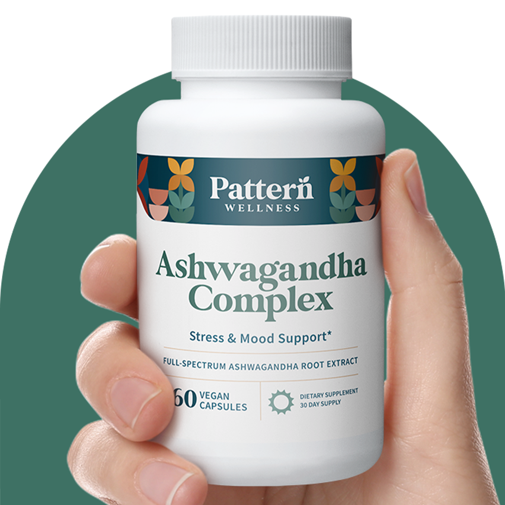 A hand holding a bottle of Pattern Wellness Ashwagandha Complex.