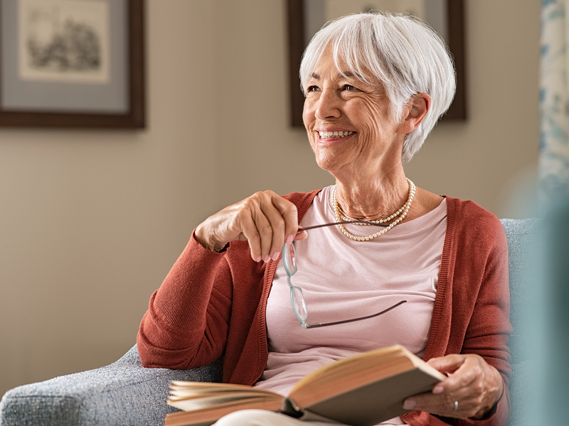 A elder woman takes off her glasses after reading.