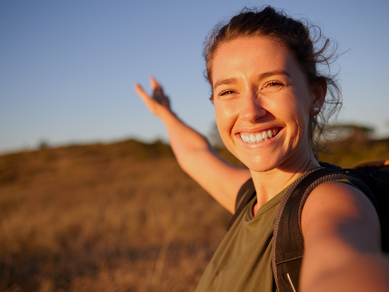 A woman joyfully extends her arms in a vast field.