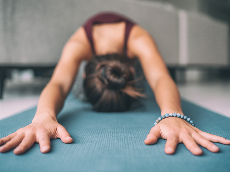 A woman practicing yoga on a blue mat.