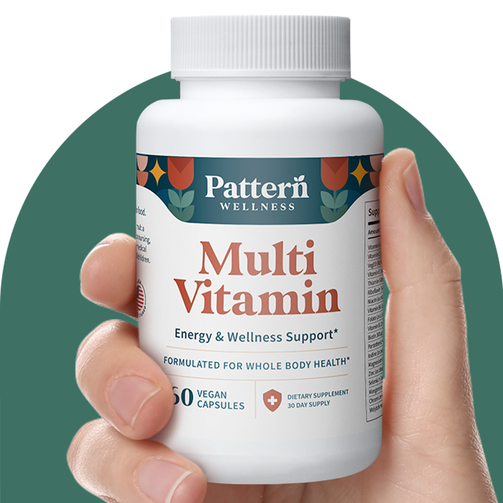 A hand holding a bottle of Pattern Wellness Multivitamin.