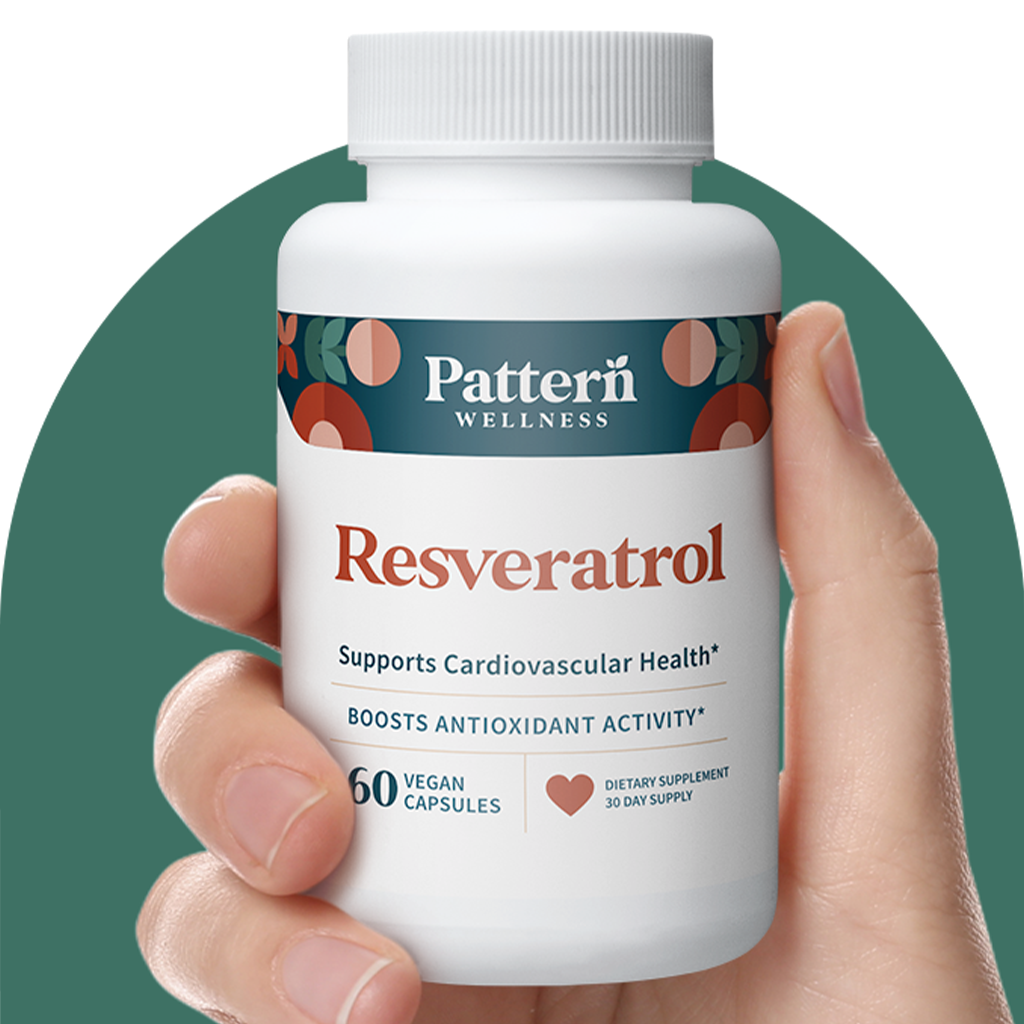 A hand holding a bottle of Pattern Wellness Resveratrol.