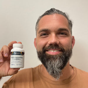 A cheerful male customer proudly displays a bottle of Pattern Wellness Ashwagandha Complex.