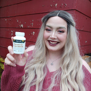 A female customer smiling while holding a bottle of Pattern Wellness Turmeric Curcumin.