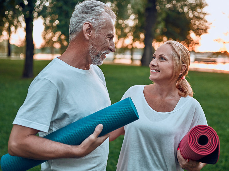 An elderly couple conversing about yoga.