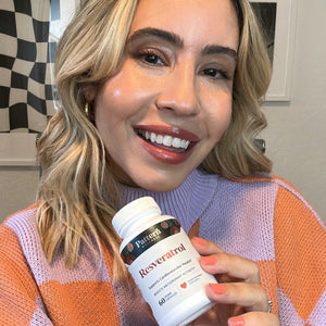 A female customer smiling while holding a bottle of Pattern Wellness Resveratrol.