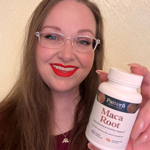 A female customer smiling while holding a bottle of Pattern Wellness Maca Root.