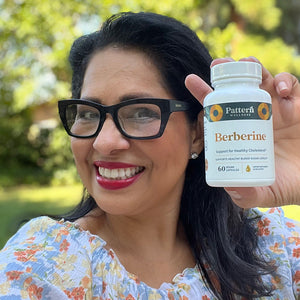 A female customer with a bright smile holding a bottle of Pattern Wellness Berberine.