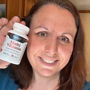 A female customer with a cheerful expression, showcasing a bottle of Pattern Wellness Multivitamin.