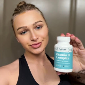 A satisfied female customer proudly displays a bottle of Pattern Wellness Vitamin B Complex.