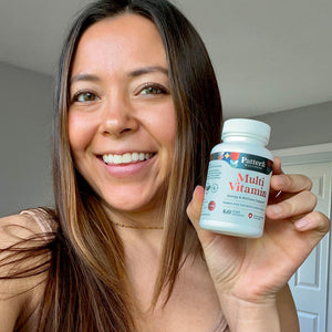 A female customer with a bright smile holding a bottle of Pattern Wellness Multivitamin.