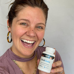 A cheerful female customer proudly displays a bottle of Pattern Wellness Probiotic.