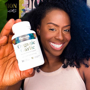 A cheerful female customer proudly displays a bottle of Pattern Wellness Organic Garlic.