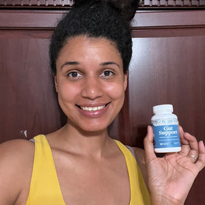 A female customer smiling while holding a bottle of Pattern Wellness Gut Support.