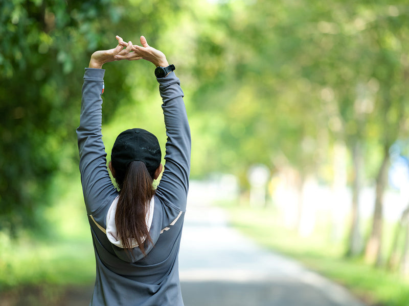 A woman stretches her arms in a tranquil park.