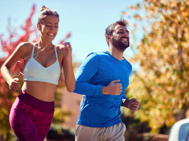 A man and woman jog together in a park.