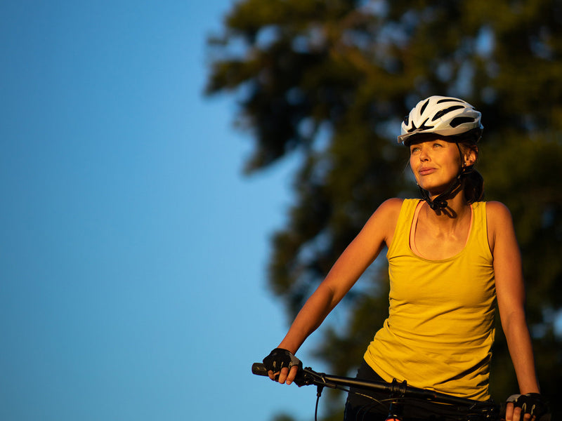 A woman on her bike, equipped with a helmet.