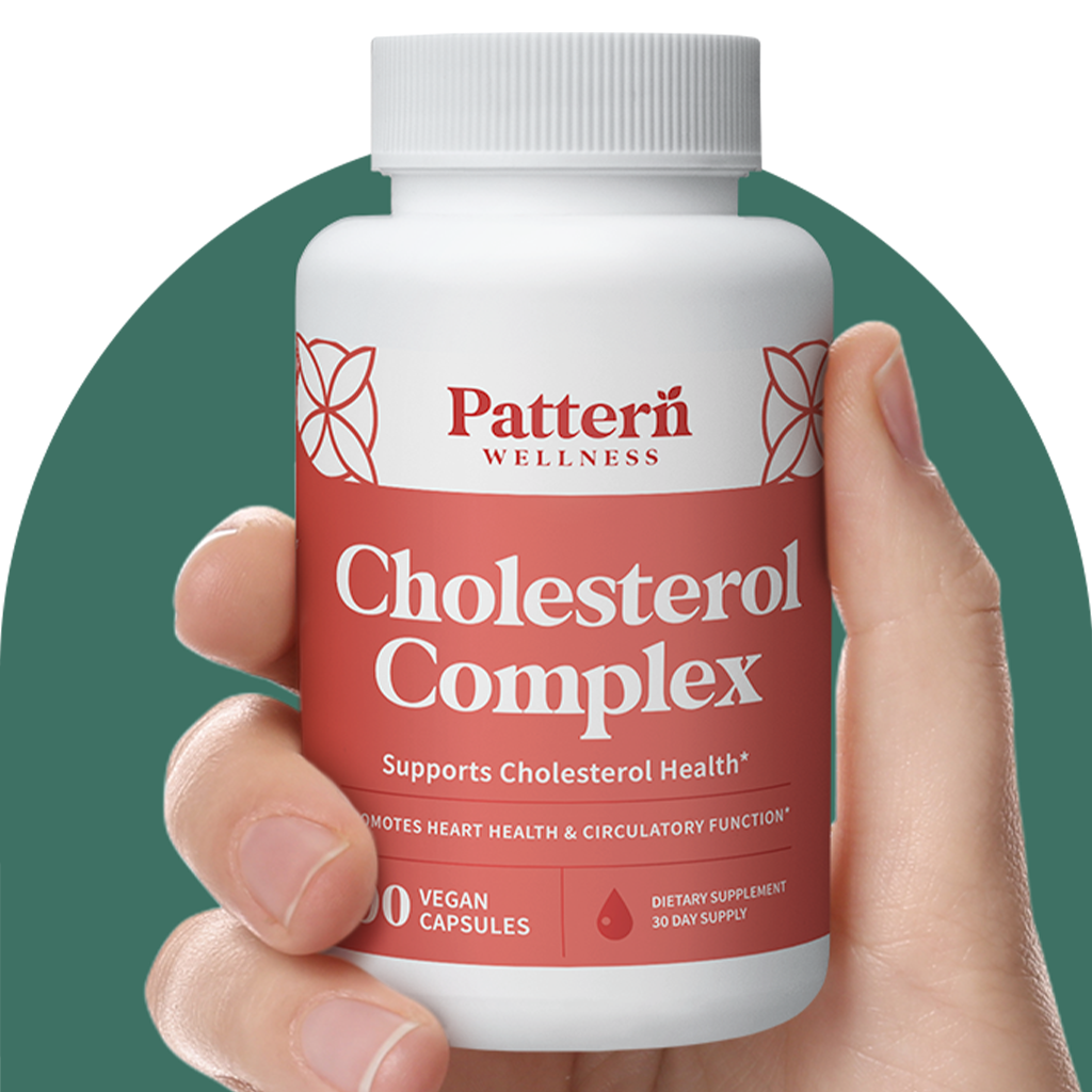 A hand holding a bottle of Pattern Wellness Cholesterol Complex.