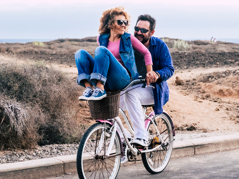 A man and woman joyfully riding a bicycle together.