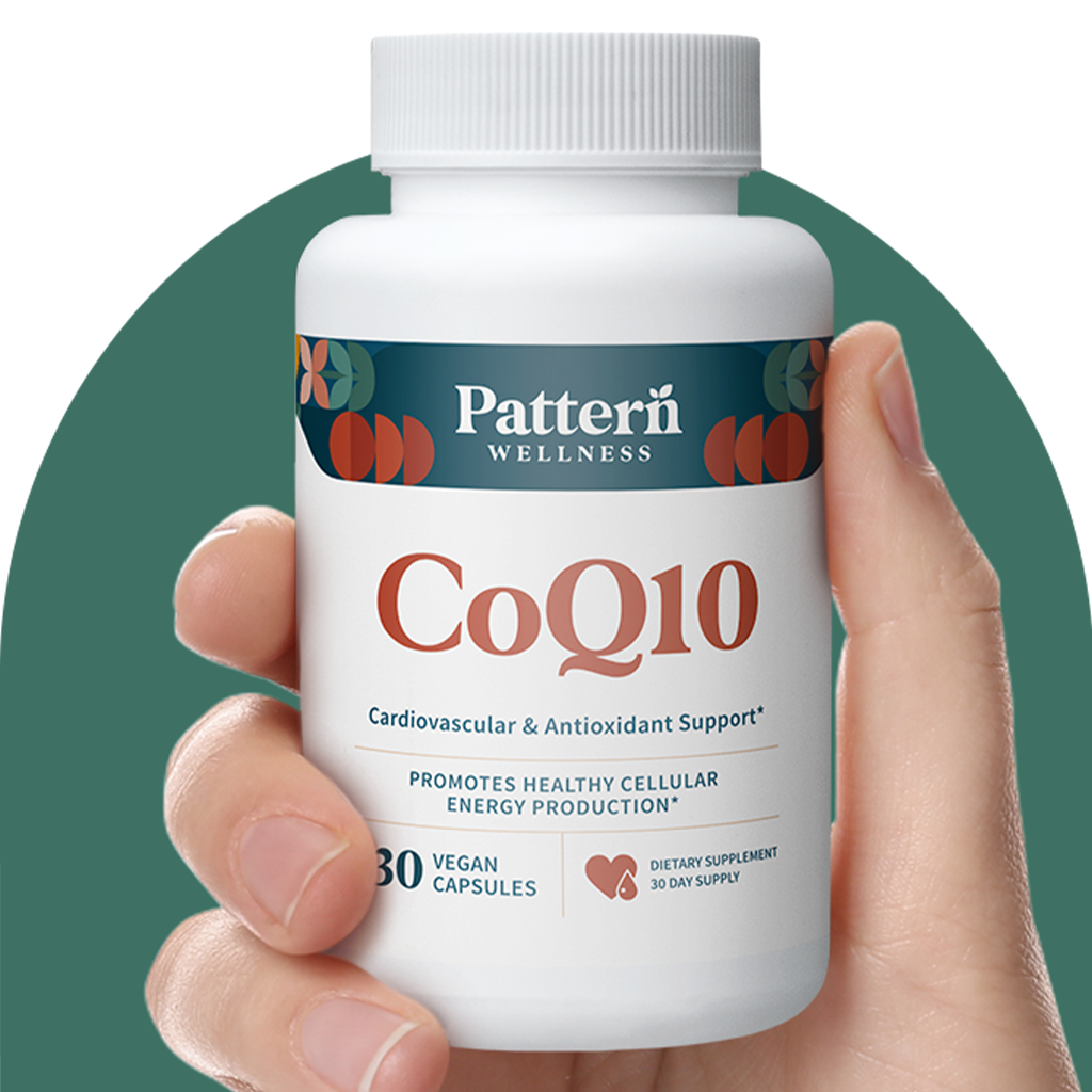 A hand holding a bottle of Pattern Wellness CoQ10.