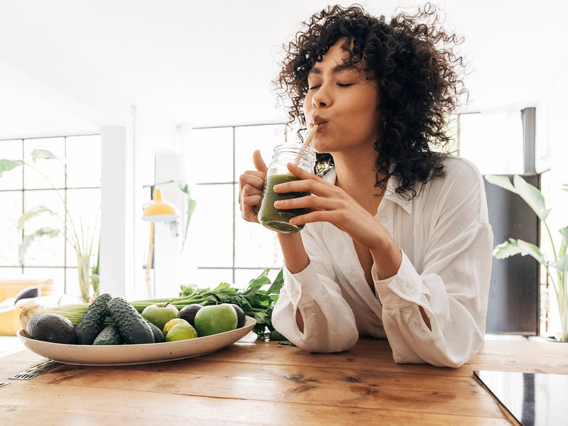 A woman enjoying a green smoothie.