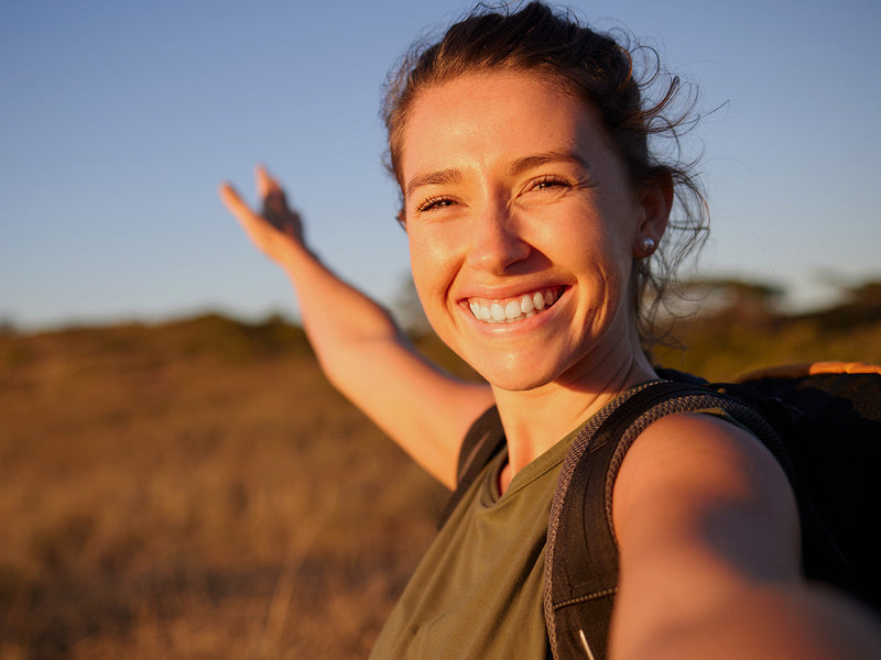 A woman stands in a field with her arms outstretched.