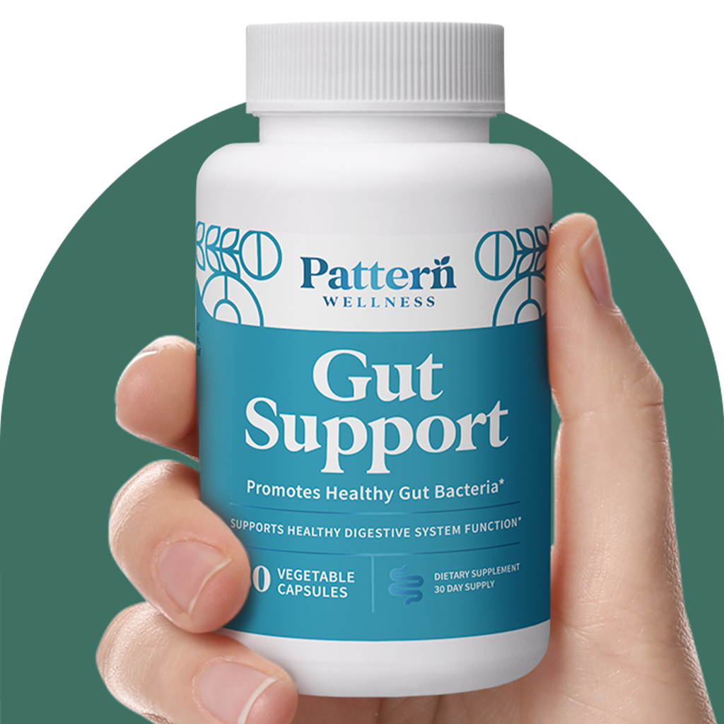 A hand holding a bottle of Pattern Wellness Gut Support.