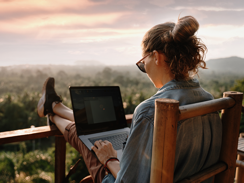 A woman comfortably sitting on a chair, using her laptop, immersed in her tasks.