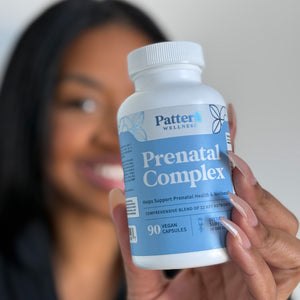 Person holding a bottle of 'Pattern Wellness Prenatal Complex' supplement.