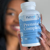 Person holding a bottle of Patten Wellness Prenatal Complex supplement.