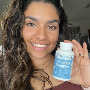Woman holding a bottle of Prenatal Complex supplement