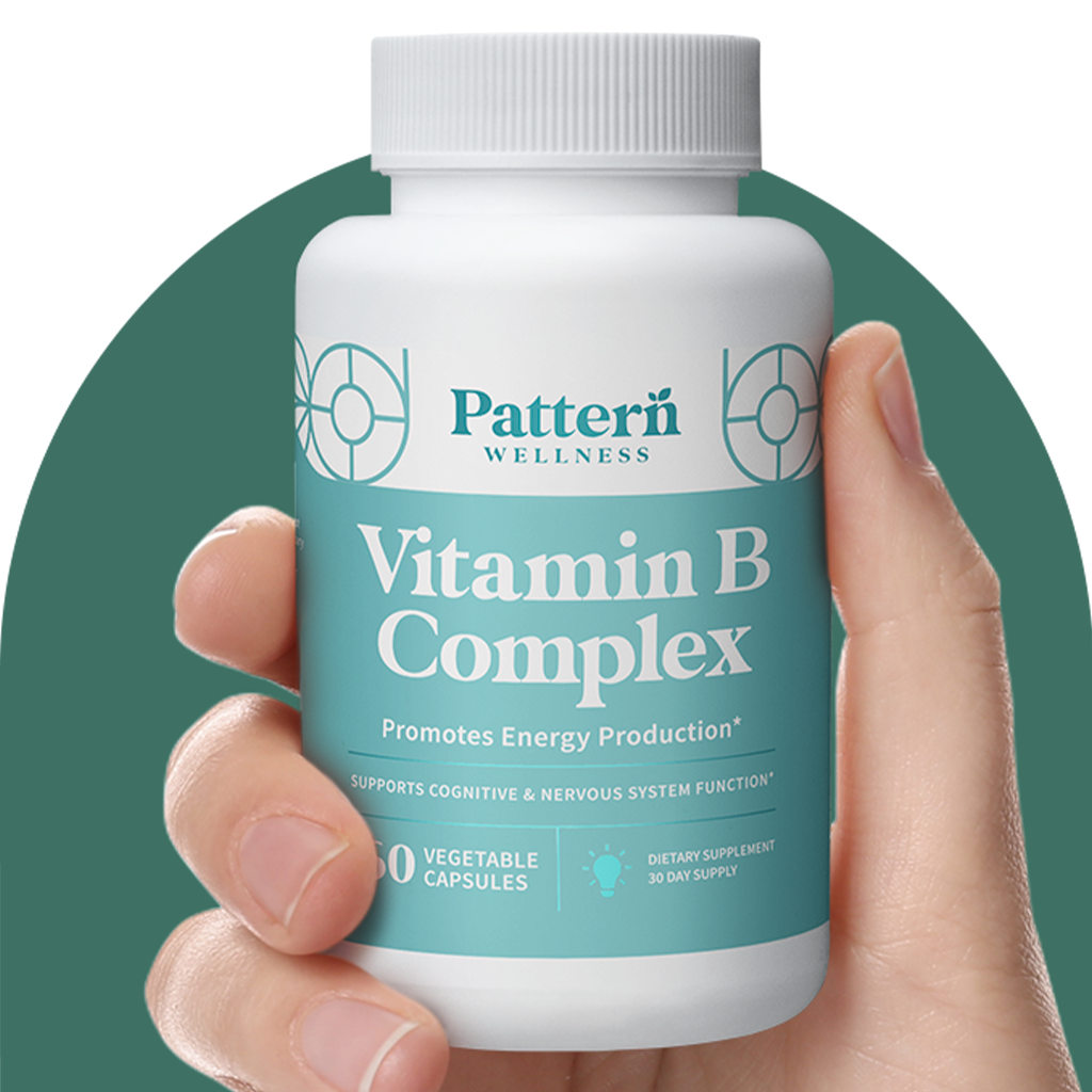 A hand holding a bottle of Pattern Wellness Vitamin B Complex.