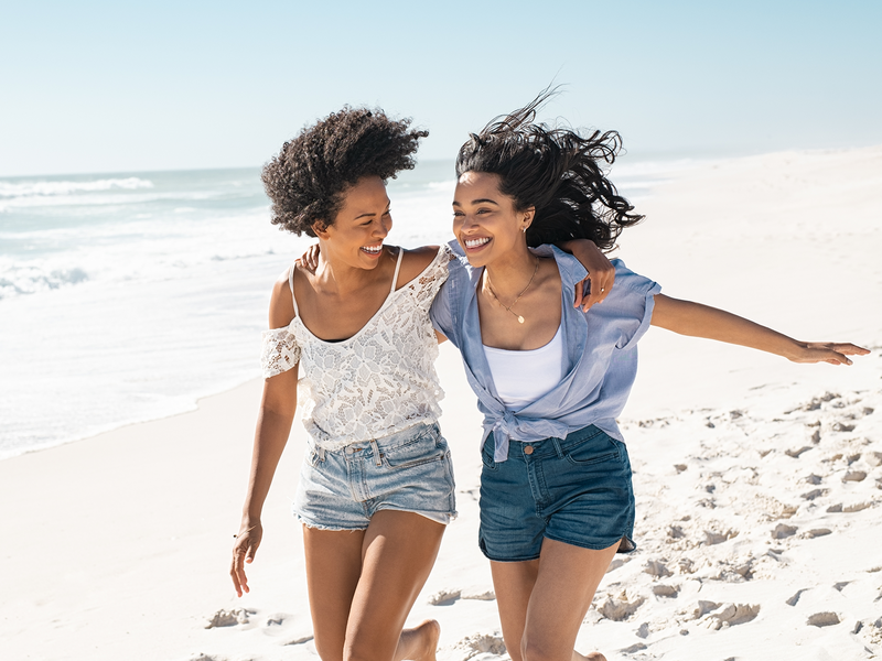 Two women joyfully walking on the beach.