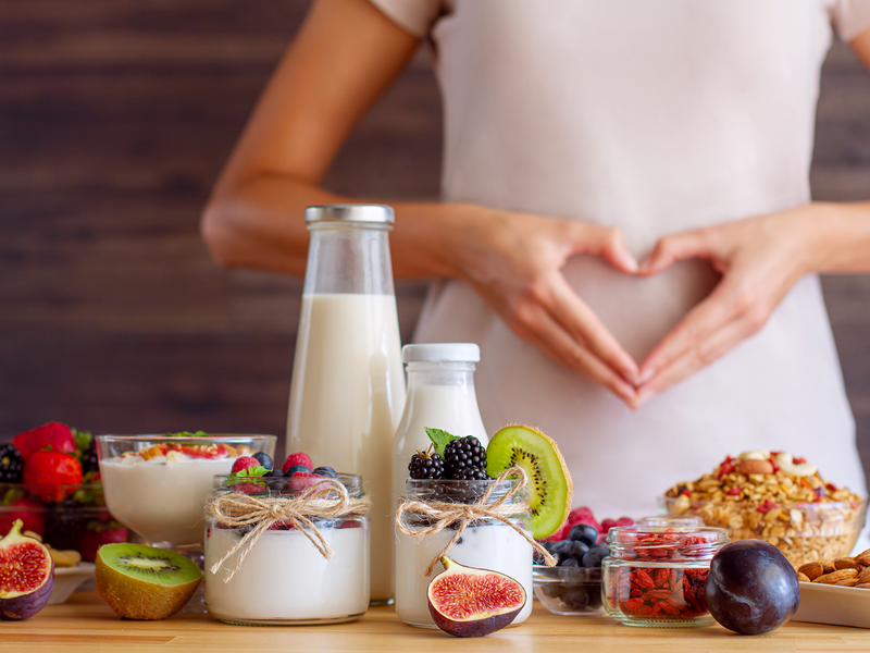 A woman creates a heart shape with her hands, surrounded by a diverse array of foods.