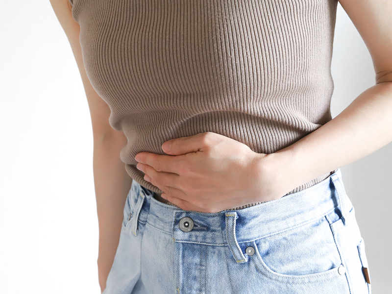 A woman is feeling her stomach with one hand.