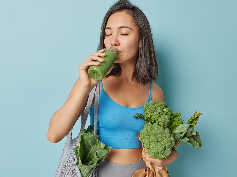 A woman is drinking a green smoothie.