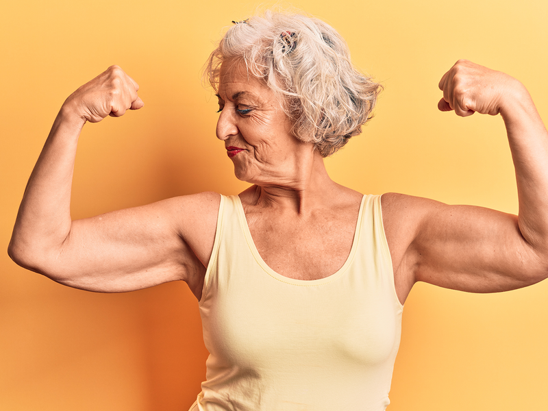 An older woman confidently flexes her muscles.