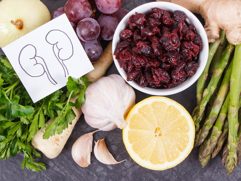 A bowl filled with fresh vegetables and fruits, featuring lemons, onions, garlic, grapes and ginger.