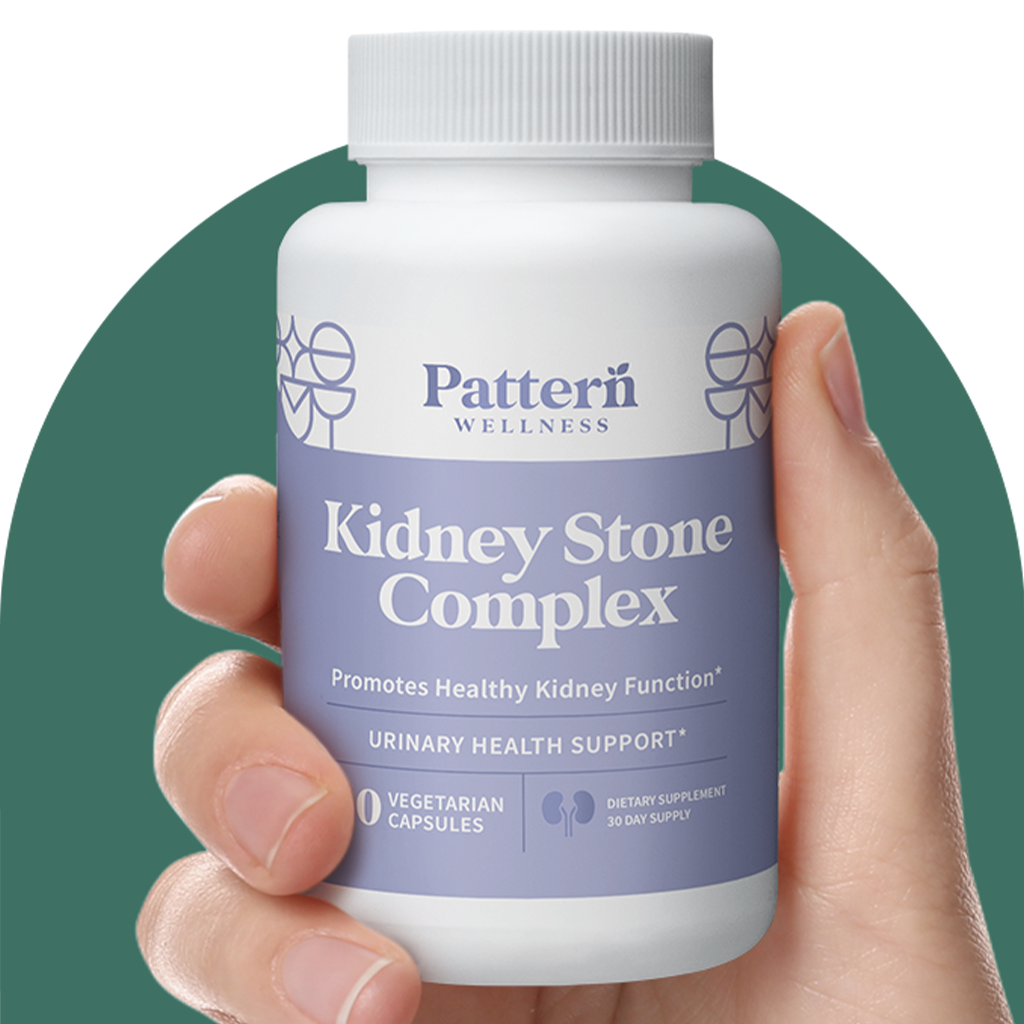 A hand holding a bottle of Pattern Wellness Kidney Stone Complex.