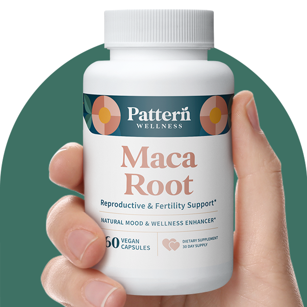 A hand holding a bottle of Pattern Wellness Maca Root.