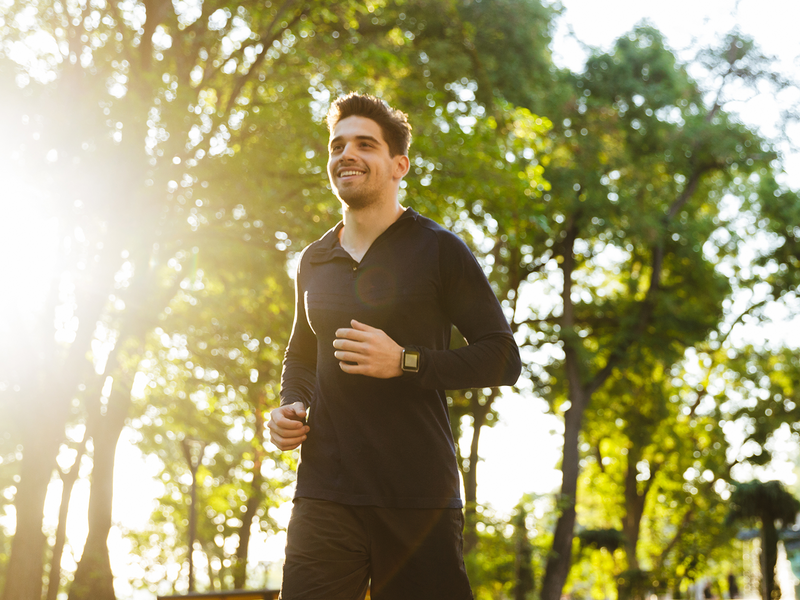 A man jogging through a lush green park.