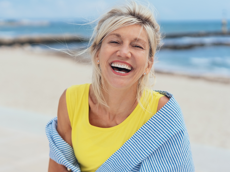 A joyful woman laughing on the beach.